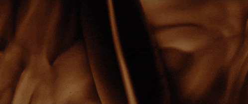 a man sitting at a desk in a dark room with a lamp