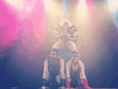 a group of women are dancing on a stage with pink lights