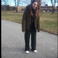 a woman is standing on a sidewalk wearing a black jacket and black pants