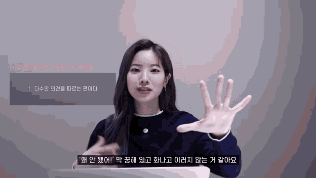 a woman in a blue sweater is making a gesture with her hand