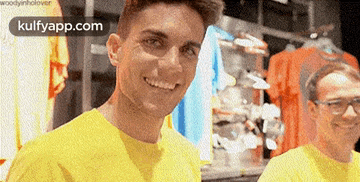a man in a yellow shirt is smiling in front of a sign that says kulfyapp.com on it