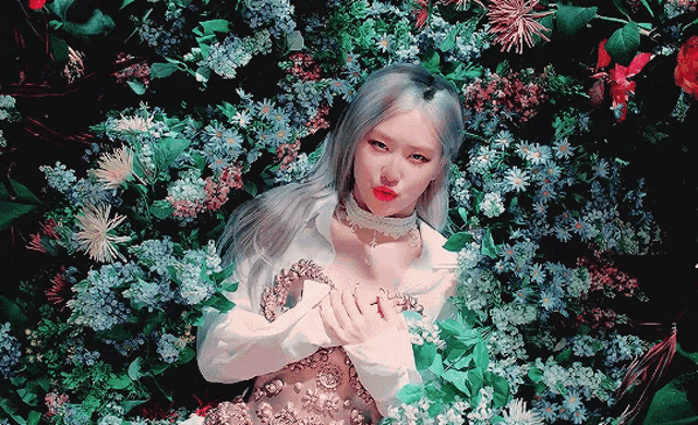 a woman in a white dress is laying in a garden of flowers