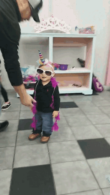 a little girl wearing sunglasses and a unicorn costume