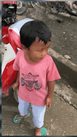 a little boy wearing a pink shirt that says o'neill four stands in front of a motorcycle