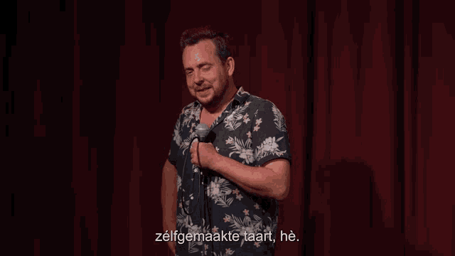 a man in a hawaiian shirt is holding a microphone and says zelfgemaakte taart he
