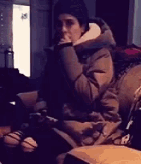 a person is sitting on a couch with their hand on their face .