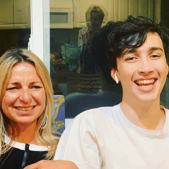 a woman and a young man are smiling for the camera