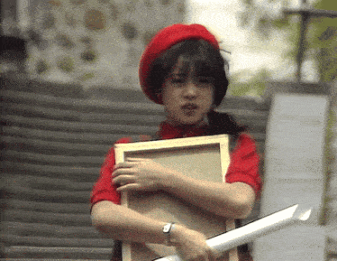 a woman wearing a red hat and a red shirt is holding a painting