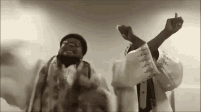 two men are standing next to each other with their arms in the air .