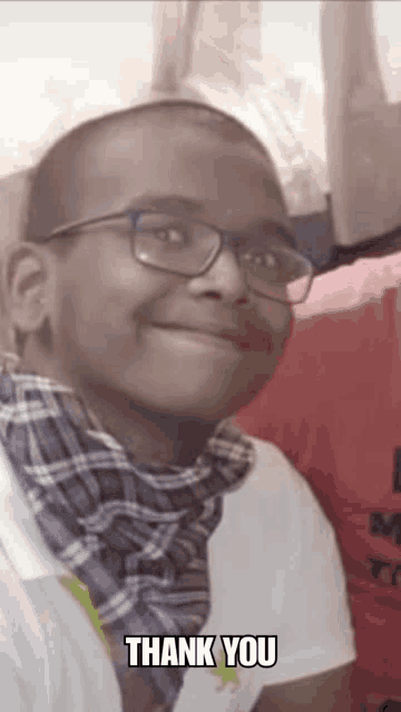 a young boy wearing glasses and a scarf is smiling and says thank you