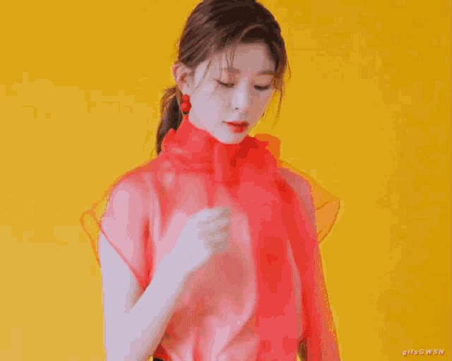 a woman in a red dress is standing in front of a yellow wall .