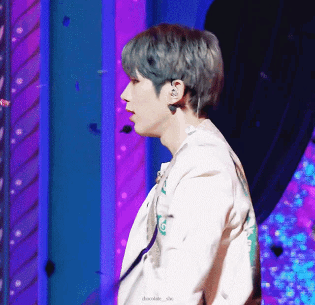 a man with blue hair is standing in front of a purple and blue background with the words chocolate_sho written below him
