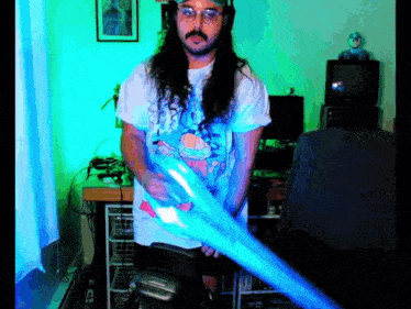 a man with long hair and glasses is holding a blue object
