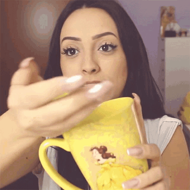 a woman is holding a yellow mug with a picture of a horse on it