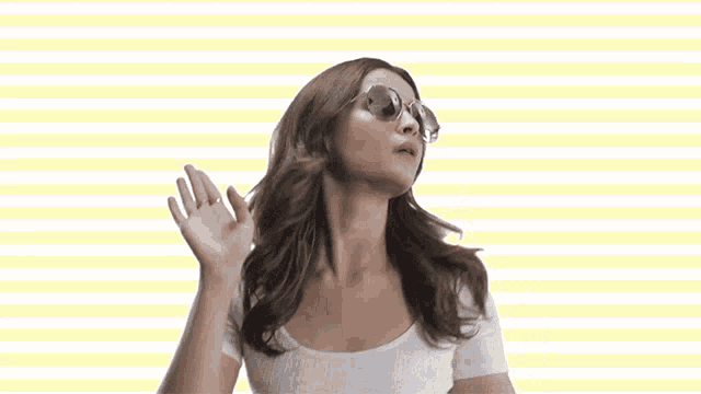 a woman wearing sunglasses and a white shirt makes a funny face
