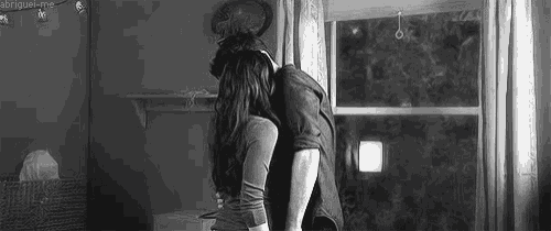 a man and a woman are hugging each other in front of a window .