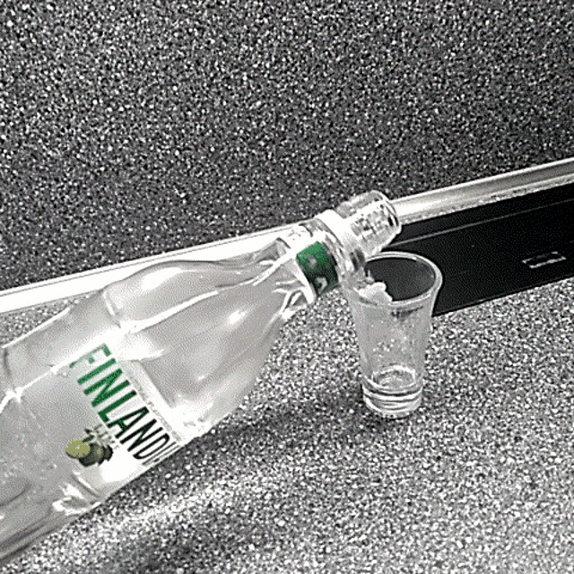 a shot glass is being poured from a bottle of finland vodka