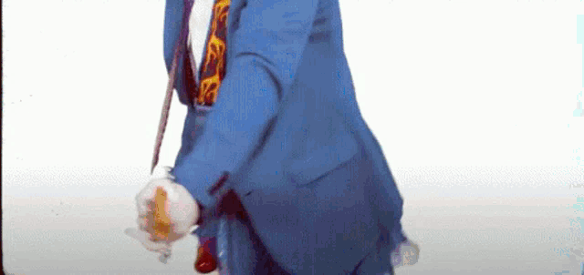 a man in a blue suit and tie is holding a cane and a bottle .