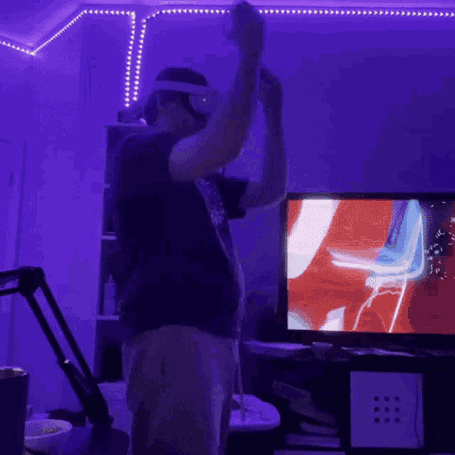 a man wearing a virtual reality headset is dancing in front of a television