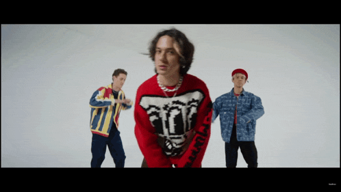 a man wearing a red sweater that says ' a ' on it is standing next to two other men