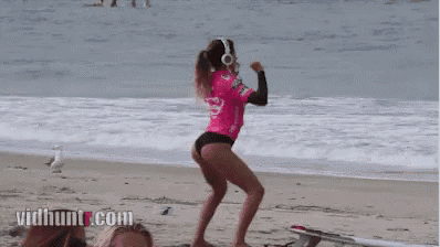 a woman wearing headphones is walking on a beach next to a surfboard with vidhunt.com written on the bottom