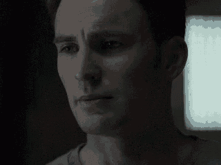 a close up of a man 's face with a sad look on his face in a dark room .
