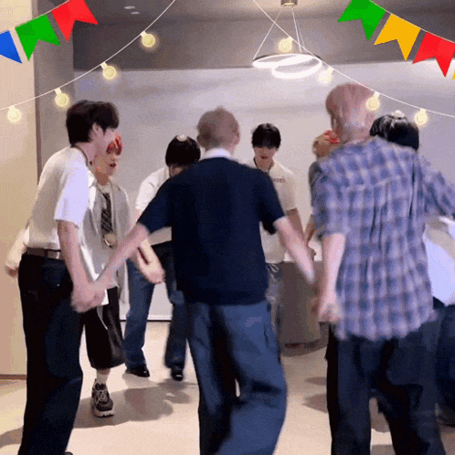 a group of people are dancing in a room with colorful flags