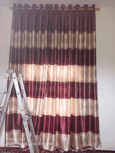 a ladder is sitting in front of a curtain that says galaxy a24 december 01 2021 12:01 pm