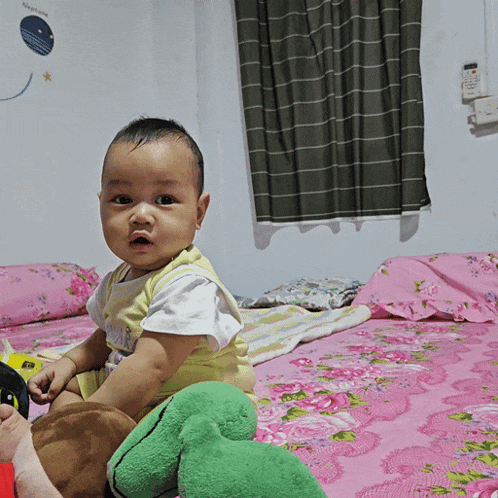 a baby sitting on a bed with a sticker on the wall that says night