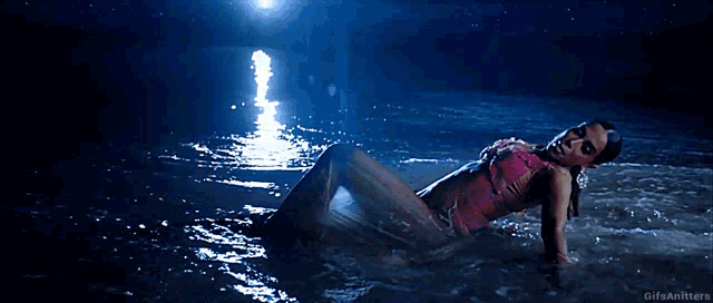 a woman in a pink swimsuit is laying in the water with the gifs anitters watermark
