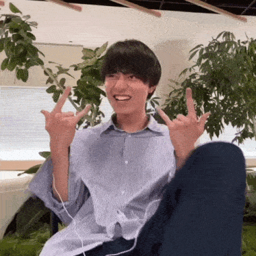 a young man in a striped shirt is making a rock sign