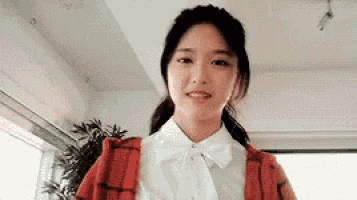 a woman wearing a red cardigan and a white shirt is smiling .