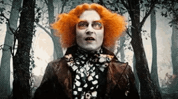 the mad hatter from alice in wonderland is standing in the woods looking at the camera .