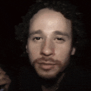 a close up of a man 's face with a beard in a dark room