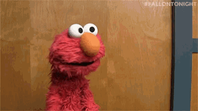 elmo from sesame street standing in front of a wooden wall