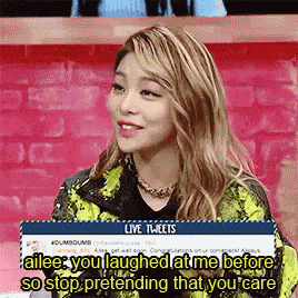 a woman is laughing while holding a sign that says live tweets .