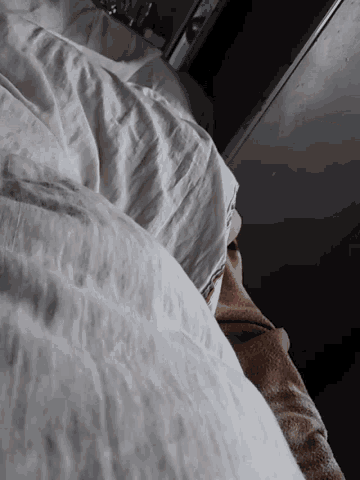 a bed with white sheets and a brown blanket on it