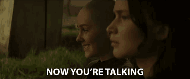 two women are sitting next to each other with the words now you 're talking behind them