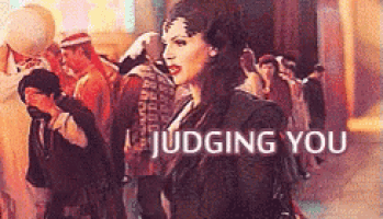 a woman in a black dress is standing in front of a crowd and the words judging you are above her
