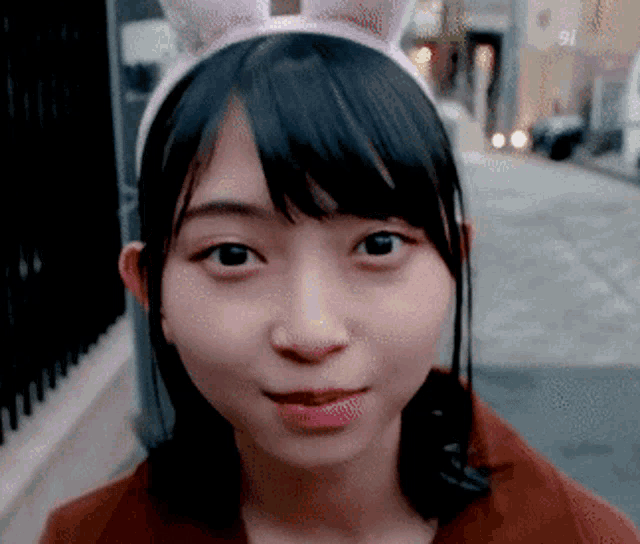 a girl wearing a headband with bunny ears is smiling and looking at the camera