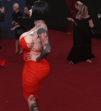 a woman in a red dress with tattoos on her arm