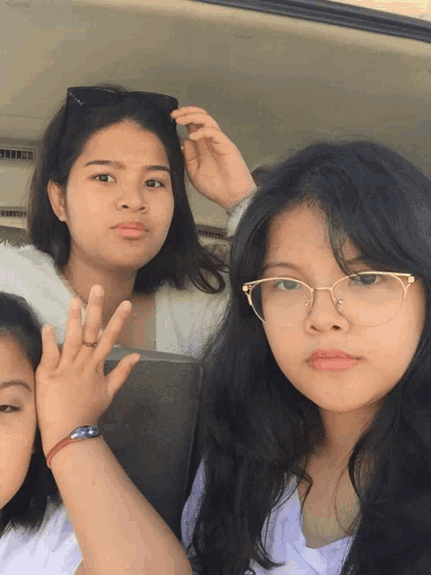 three girls are posing for a picture and one of them has glasses