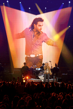 a man singing in front of a large screen