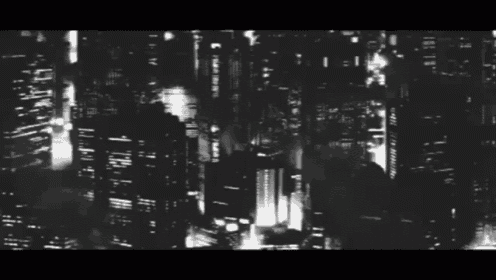 a black and white photo of a city at night with a few buildings lit up