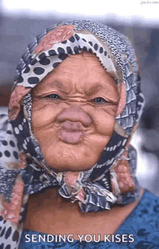 an elderly woman wearing a scarf around her head is making a funny face and sending you kisses .