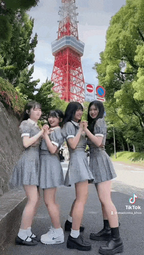 a group of young girls are standing next to each other in front of a tower .