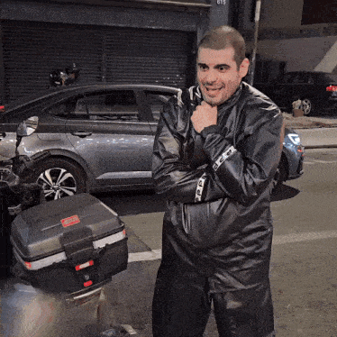 a man in a black leather jacket stands in front of a car with the number 615 on it