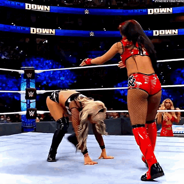 two women are wrestling in a ring with a sign that says " down " on it