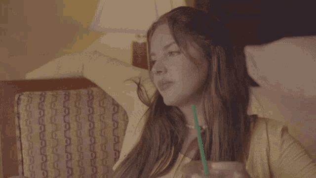 a woman is sitting in a chair with a green straw in her hand