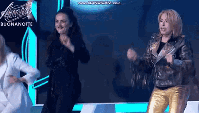 a group of women are dancing on a stage in front of a sign that says amici